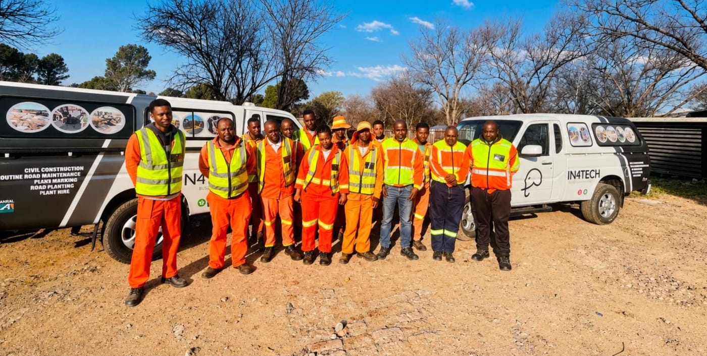 The In4Tech team in high visibility workwear beside company vehicles